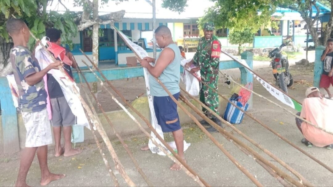 Babinsa Bantu Warga Pasang Umbul-Umbul Sambut HUT Jemaat dan Paskah