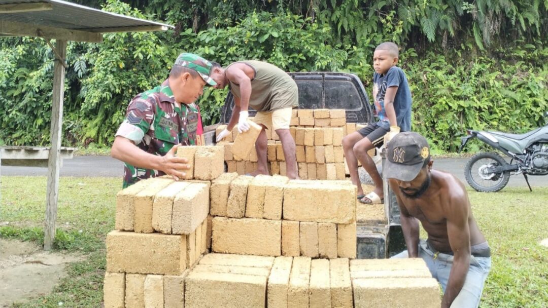 Babinsa Supiori Selatan Bantu Warga Turunkan Batu Tela untuk Pembangunan Rumah