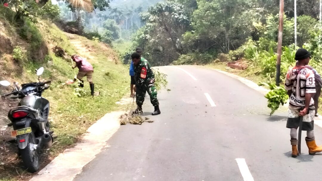 Babinsa dan Warga Bersihkan Sisa Pembabatan Rumput di Jalan Kampung Nermnu