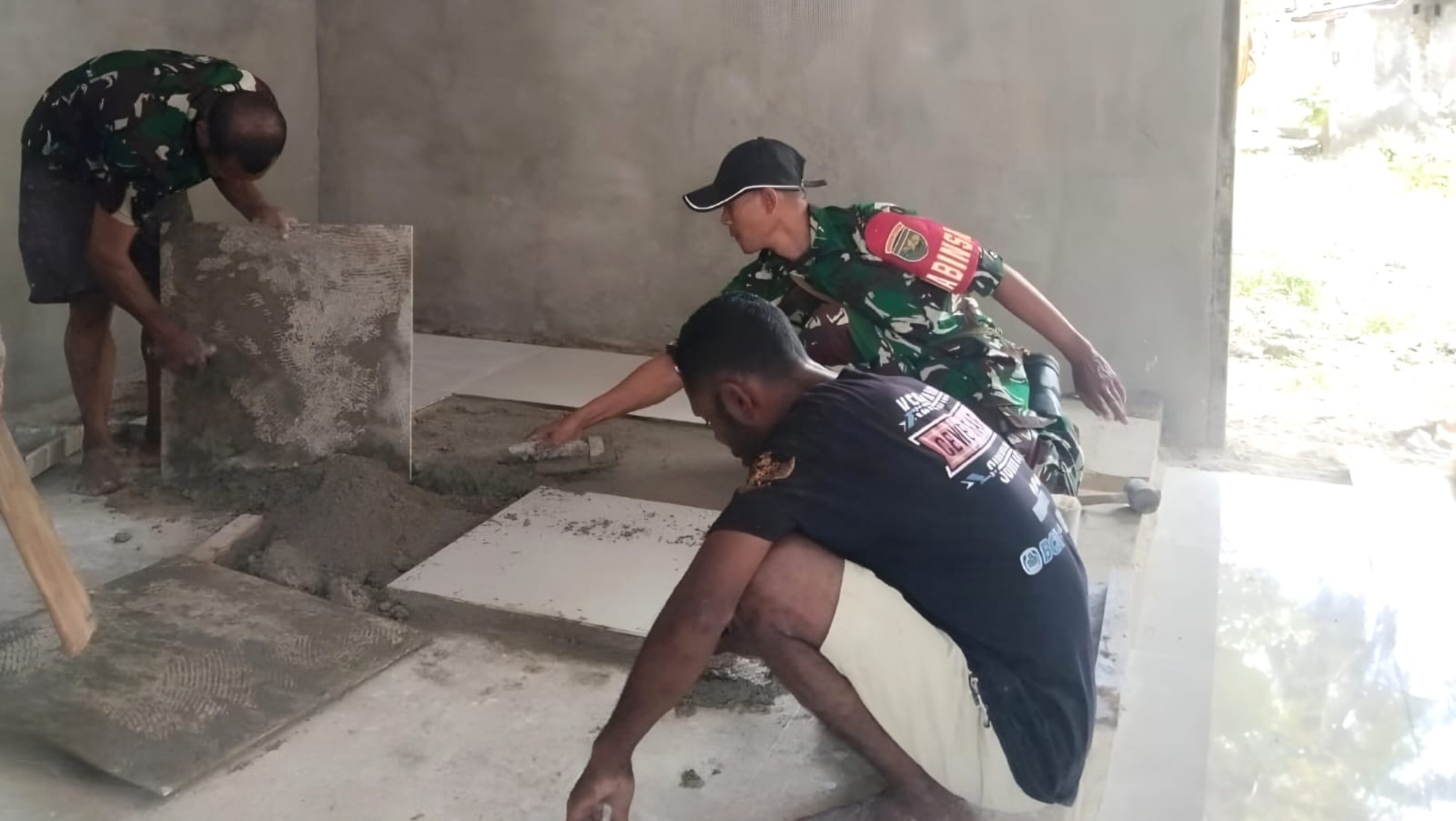 Babinsa Warsa dan Warga Gotong-Royong Pasang Keramik Rumah Sembahyang Ayaisya